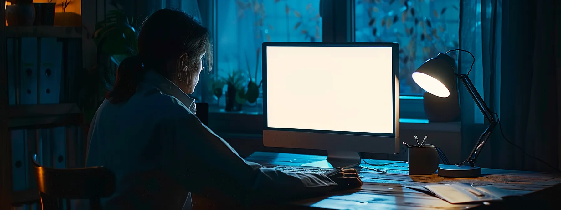 a person sitting at a desk, staring at a blank computer screen with a look of hesitation and uncertainty.